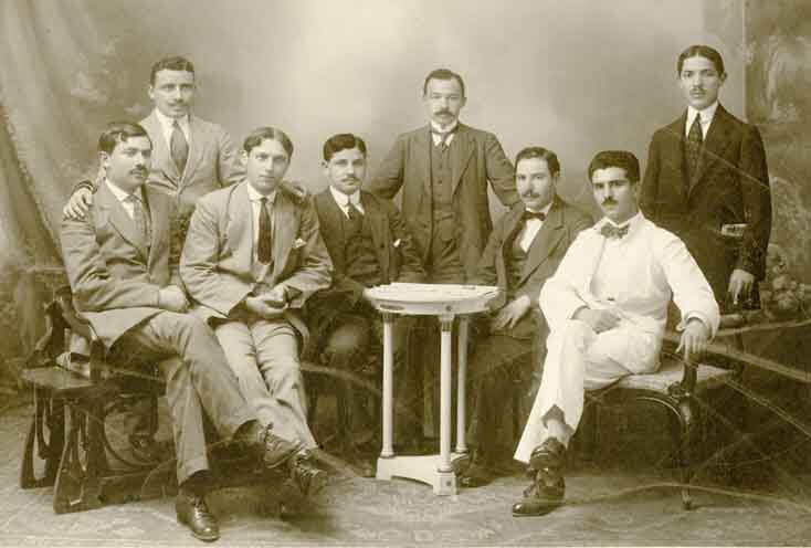 A group of eight men sitting around a table.