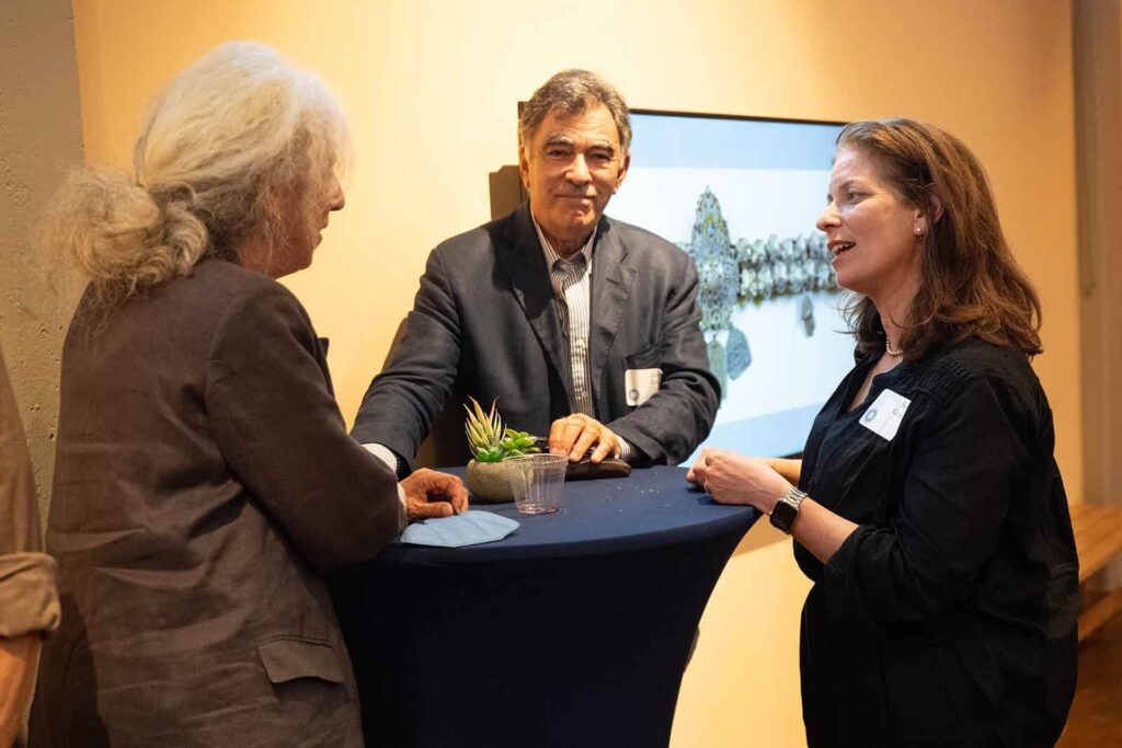 Three people standing around a table in conversation