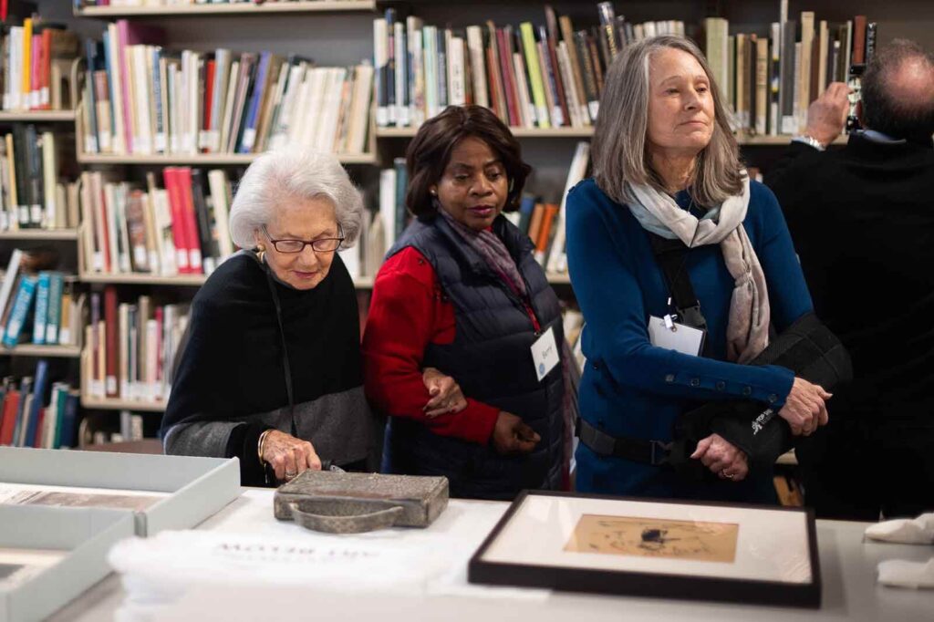 3 women look at objects in a museum study room