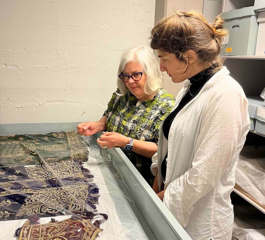 Two women in museum storage looking at textiles